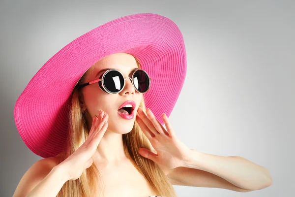 Ekspresyjny młody model w różowy kapelusz z okulary na szarym tle — Zdjęcie stockowe
