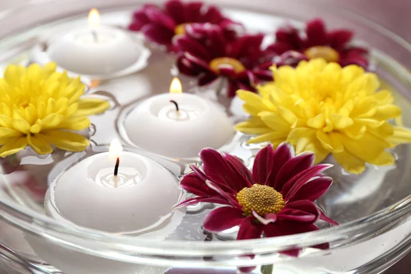 Bol d'eau de spa avec des fleurs et des bougies, gros plan — Photo