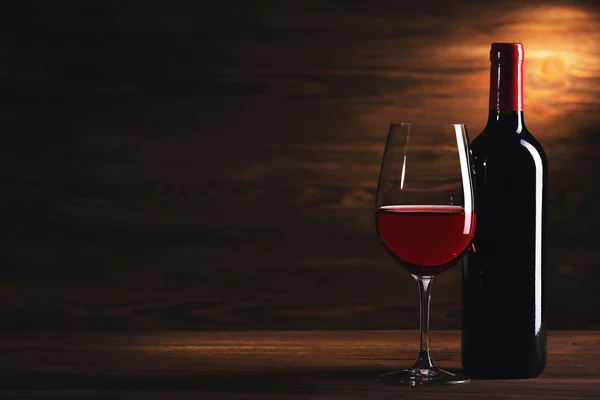 Wijnglas en fles op houten achtergrond — Stockfoto