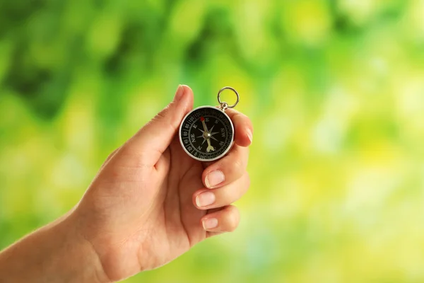 Kvinnlig hand med kompass på ljusa suddig bakgrund — Stockfoto