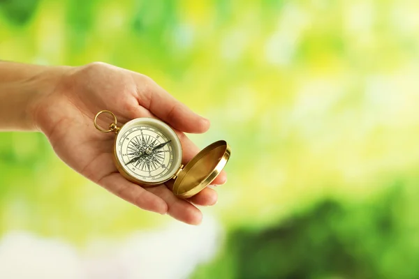 Mano femenina con brújula sobre fondo borroso brillante — Foto de Stock