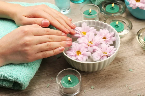 Female hands with bowl of aroma spa water on wooden table, closeup — Stock Photo, Image