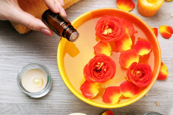 Kadın el özü şişe ve aroma spa su üzerinde ahşap masa, closeup kase — Stok fotoğraf