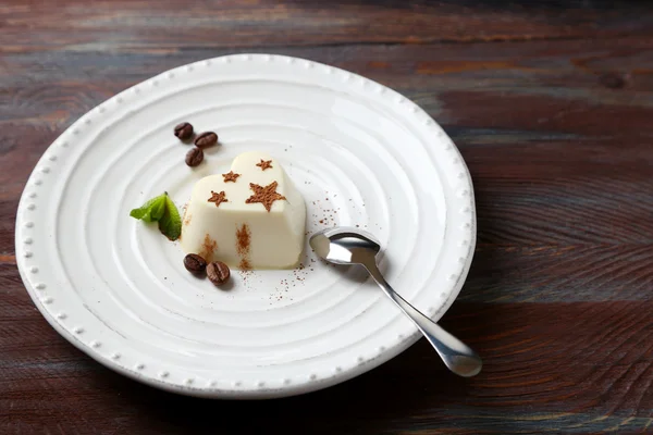 Gustoso dolce di panna cotta su piatto, su tavola di legno — Foto Stock