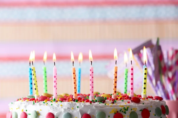 Tarta de cumpleaños con vela sobre fondo a rayas de colores —  Fotos de Stock