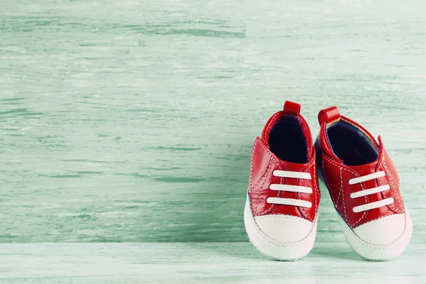 Ahşap arka plan üzerinde renkli yürümeye başlayan çocuk ayakkabı — Stok fotoğraf
