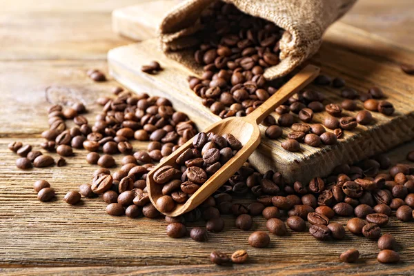 Kávová zrna na dřevěný stůl, detail — Stock fotografie