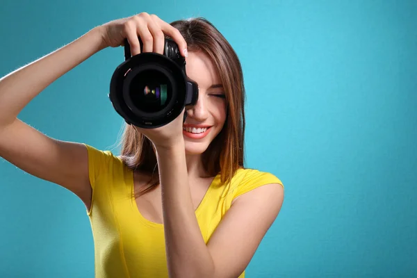 Mladá žena fotograf fotí na modrém pozadí — Stock fotografie