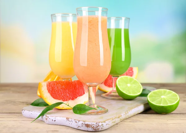 Frische Sommercocktails mit Früchten auf Holztisch vor hellem, verschwommenem Hintergrund — Stockfoto