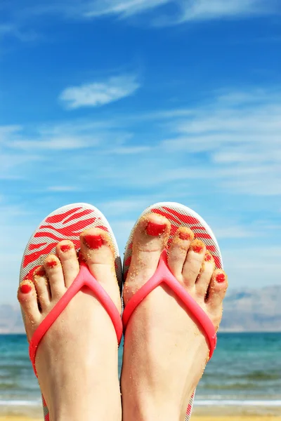 Closeup of bright flip flops and legs on sea background — Stock Photo, Image
