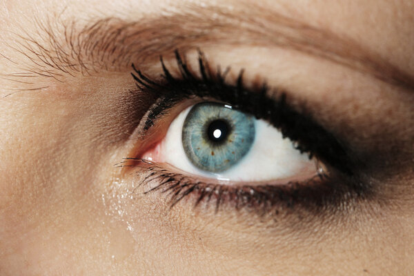 Глаз молодой женщины со слезоточивой каплей вблизи
