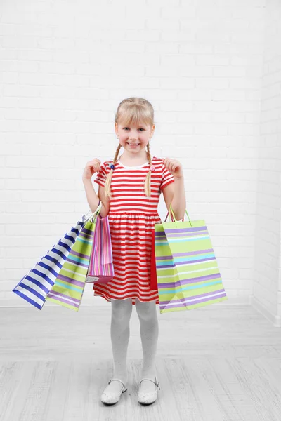 Hermosa niña con bolsas de compras en la habitación — Foto de Stock
