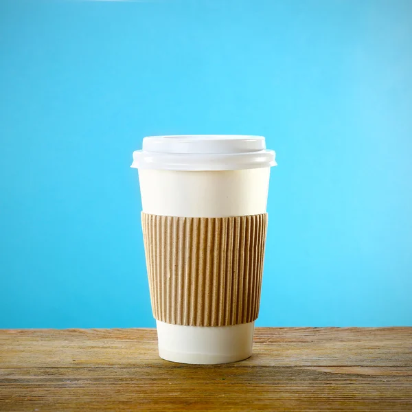 Paper cup on wooden table on blue background — Stock Photo, Image