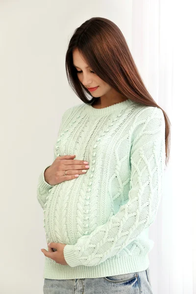 Pregnant woman on white wall background, indoors — Stock Photo, Image