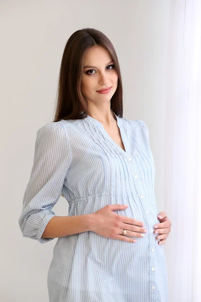 Gravid kvinna på vit vägg bakgrund, inomhus — Stockfoto