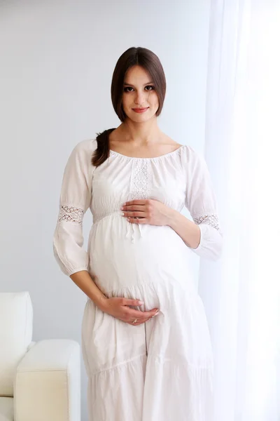 Femme enceinte sur fond de mur blanc — Photo