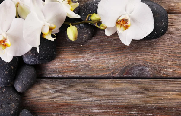 Piedras de spa y flor de orquídea sobre fondo de madera —  Fotos de Stock