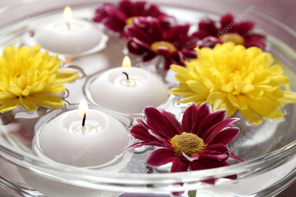 Bowl of spa water with flowers and candles, closeup