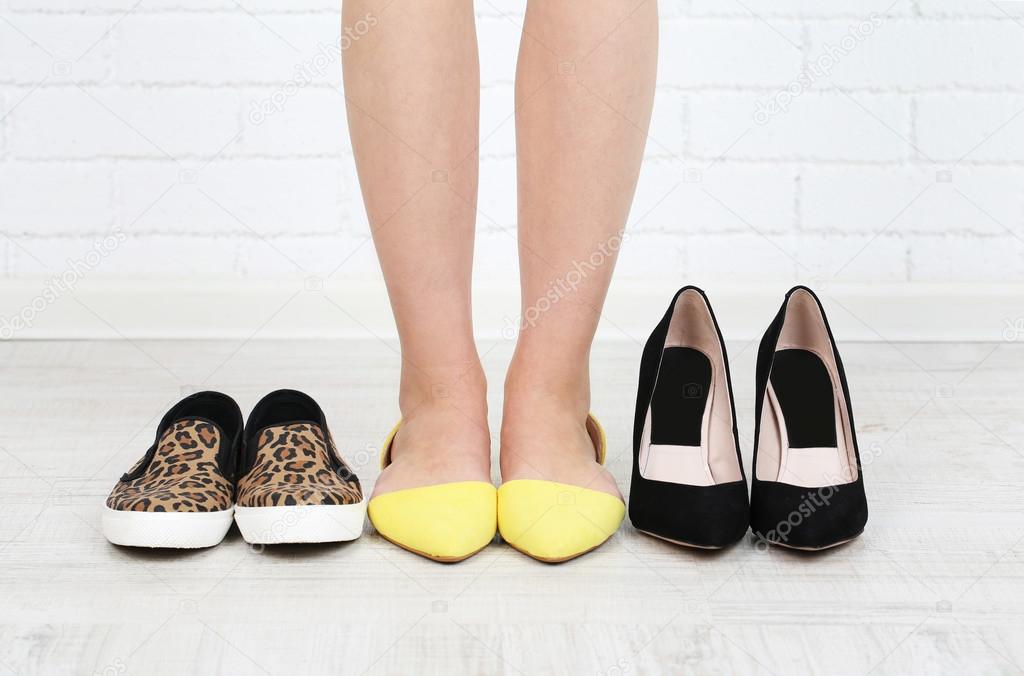 Girl chooses shoes in room on grey background