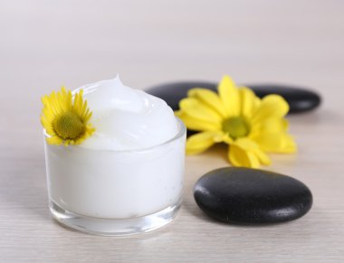 Çiçek ve spa taşlar ahşap arka plan üzerinde kozmetik krem