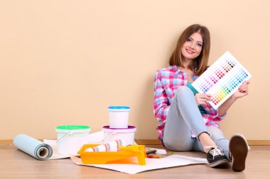 Güzel kız boyama duvar için ekipman ile katta oturan