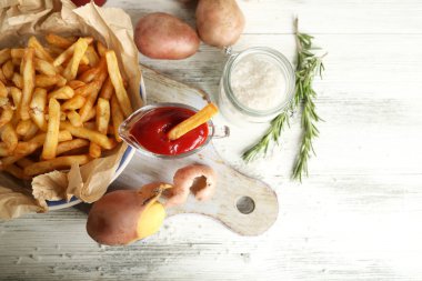 Tahtada patates kızartması, ahşap masa arkasında.