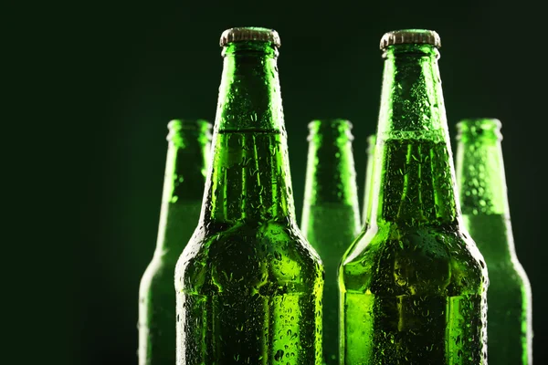 Glazen flessen bier op donkere groene achtergrond — Stockfoto