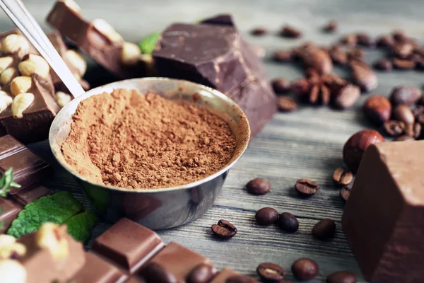 Çikolata fındık, otlar ve ahşap masa, closeup üzerinde kahve çekirdekleri ile kümesi — Stok fotoğraf