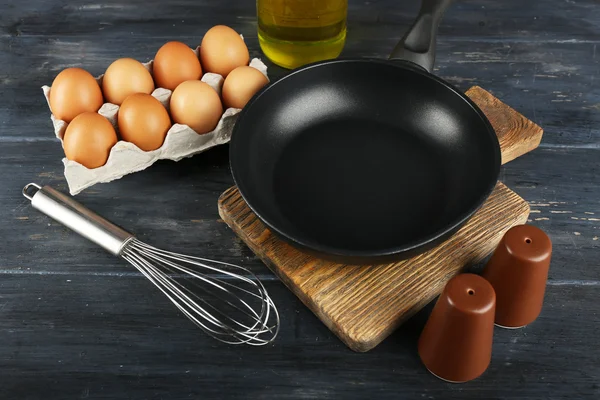 Zátiší s vejci a pan na dřevěné pozadí — Stock fotografie