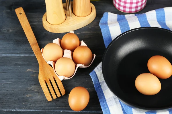 Stilleven met eieren en pan op houten achtergrond — Stockfoto