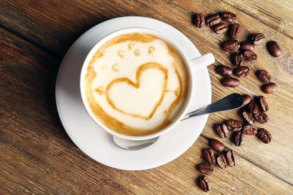 Tasse Kaffee Latte Art mit Körnern auf Holzgrund — Stockfoto