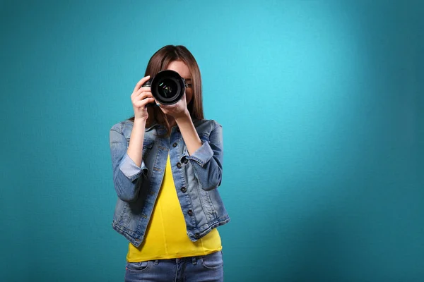 Mladá žena fotograf fotí na modrém pozadí — Stock fotografie