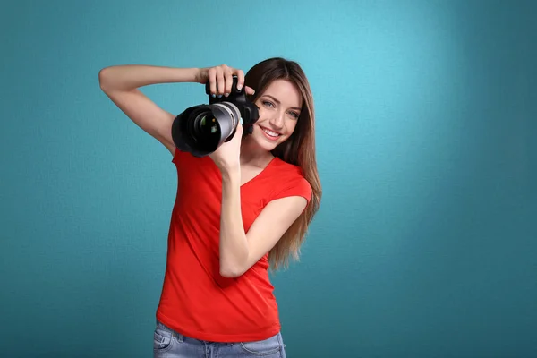 Jovem fotógrafa tirar fotos no fundo azul — Fotografia de Stock