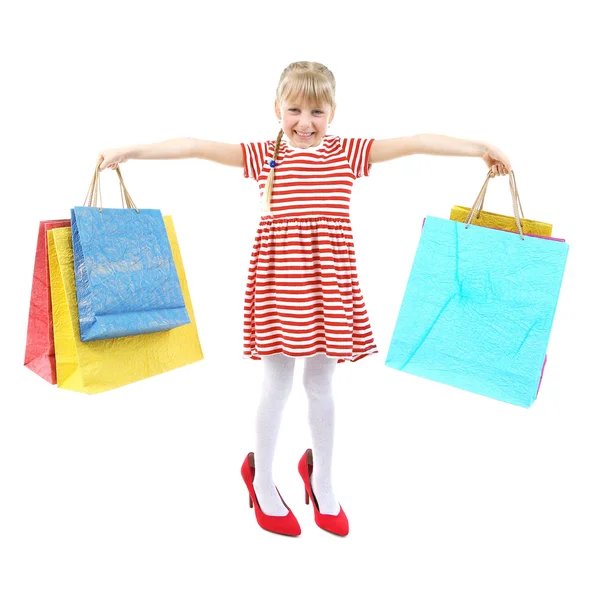 Hermosa niña en los zapatos de mamá con bolsas de compras aisladas en blanco — Foto de Stock