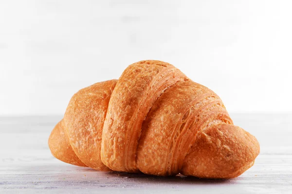 Ízletes croissant-t tábla-ra könnyű háttér — Stock Fotó