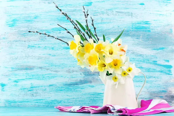 Fresh narcissus flowers with willow sprigs on color wooden background — Stock Photo, Image