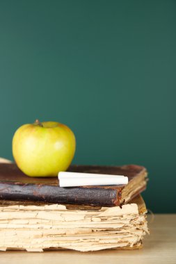 Eski kitaplar, elma ve tebeşir yazı tahtası arka plan üzerinde