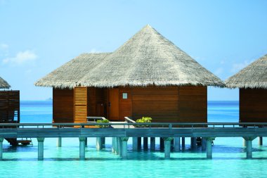 Water villas over blue ocean in Baros Maldives clipart