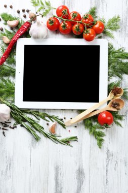Taze otlar, domates ve baharat ahşap arka plan üzerinde dijital tablet