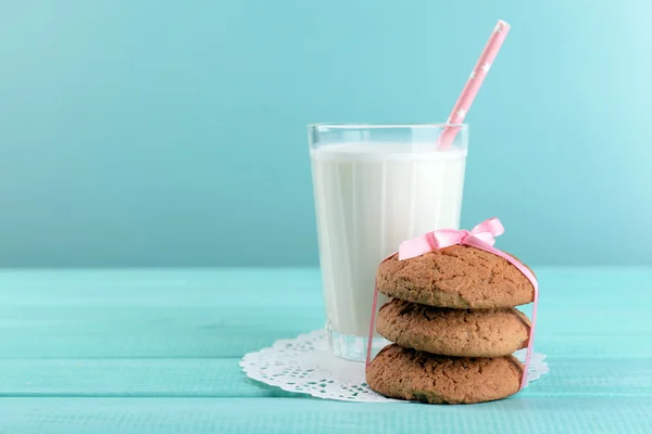 Ízletes cookie-k és a pohár tejet, színes fából készült háttér — Stock Fotó