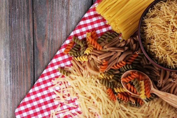 Diferentes tipos de pasta en servilleta sobre fondo de madera —  Fotos de Stock