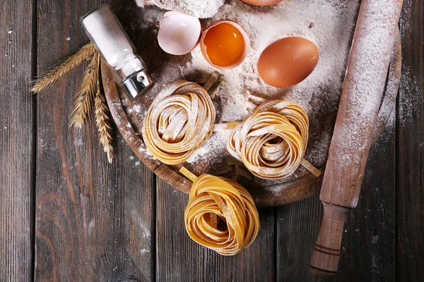 Raw homemade pasta and ingredients for pasta on wooden background — Stock Photo, Image