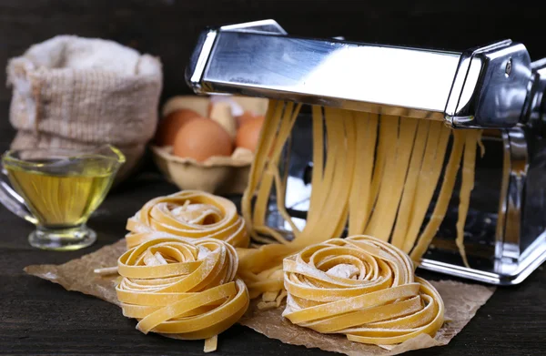 Máquina de fazer macarrão de metal e ingredientes para massas em fundo de madeira — Fotografia de Stock