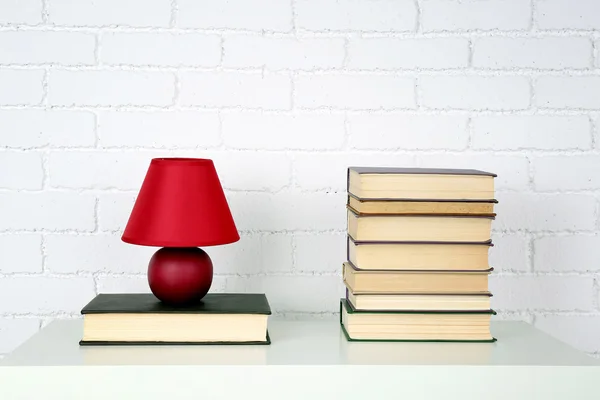 Estante de madera con libros y lámpara sobre fondo de pared de ladrillo — Foto de Stock