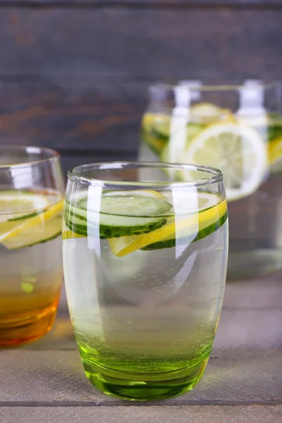 Agua dulce con limón y pepino en cristalería sobre fondo de madera — Foto de Stock