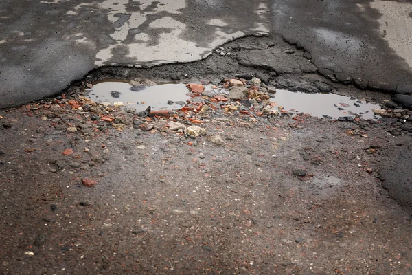 Nagyon rossz minőségű úton potholes és pocsolya — Stock Fotó