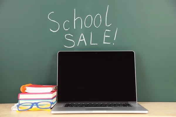 Laptop på bord, på gröna blackboard bakgrund — Stockfoto