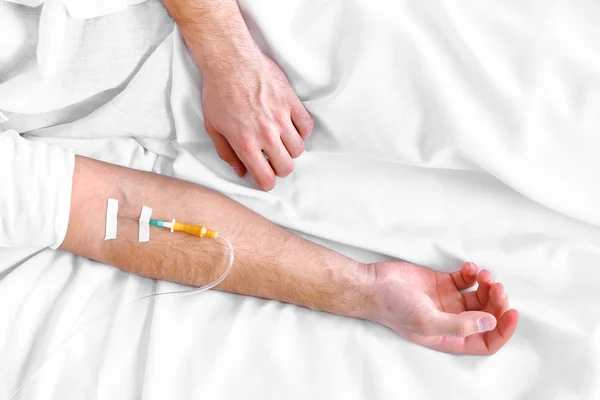 Man hand with dropper needle on bed close-up — Stock Photo, Image