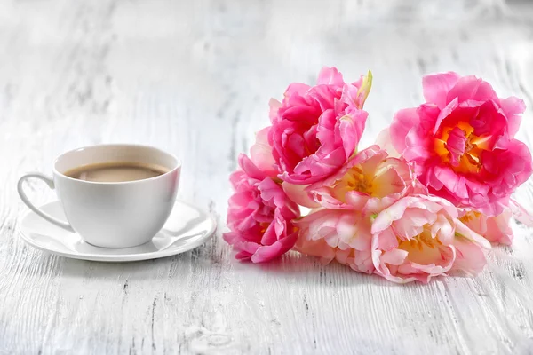 Розовые тюльпаны с чашкой кофе на деревянном фоне — стоковое фото