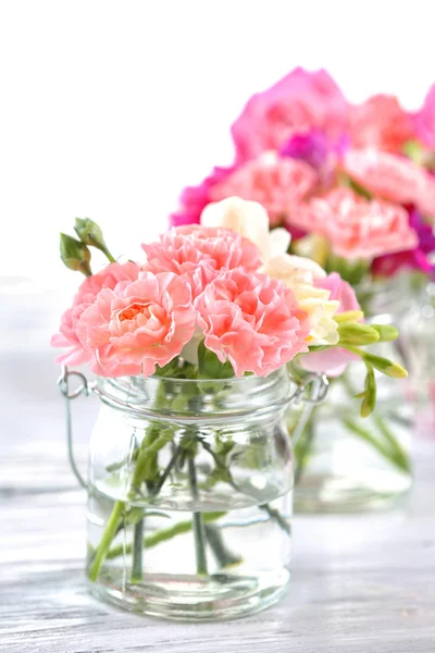 Beautiful spring flowers in glass bottles — Stock Photo, Image